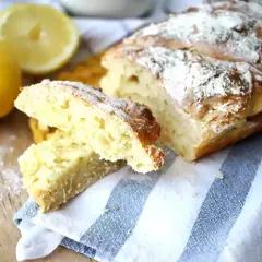 Pain sans levure, doré et saupoudré de farine, avec des citrons frais à côté.