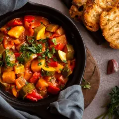 Ratatouille colorée dans un plat noir, servie avec des toasts grillés. Parfait pour savoir que manger avec une ratatouille.