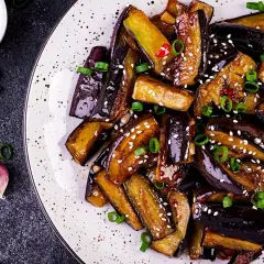 Aubergines poêlées, caramélisées et garnies de sésame et ciboule. Une recette simple et savoureuse pour sublimer ce légume.
