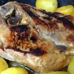 Rouelle de porc dorée et juteuse, accompagnée de pommes de terre fondantes, prête à être dégustée.