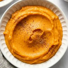 Un bol de purée de patate douce onctueuse, saupoudrée d'herbes. Un délice réconfortant.