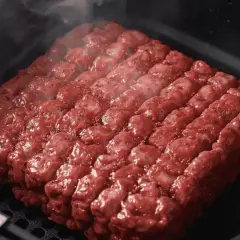 Un steak haché carré, assaisonné, cuit à la perfection dans un air fryer, dégageant une légère vapeur.
