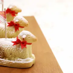 Trois agneaux en biscuit, saupoudrés de sucre glace et ornés de rubans rouges, rappellent la recette lamala grand-mère.