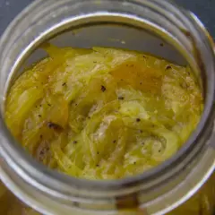 Compotée d'oignons caramélisés dans un bocal en verre, prête à être dégustée.