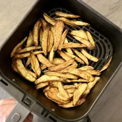 Un panier d'air fryer rempli de frites dorées et croustillantes, prêtes à être dégustées.