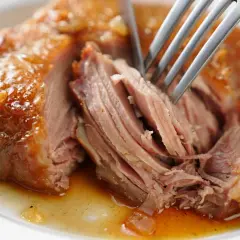 Une rouelle de porc juteuse, effilochée à la fourchette, baignant dans sa sauce dorée. Un délice pour une recette de rouelle de porc réussie.