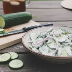 Une délicieuse salade de concombre crémeuse, garnie d'oignons rouges et d'aneth, prête à être dégustée par une chaude journée.