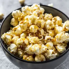 Un bol rempli de pop corn sucré, avec quelques grains éparpillés autour. Parfait pour une soirée cinéma !