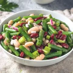 Salade colorée de haricots verts, haricots blancs et haricots rouges, avec des oignons rouges et du céleri. Un plat frais et savoureux.