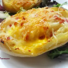 Une pomme de terre farcie, gratinée au fromage et garnie de lardons, servie avec une salade verte.
