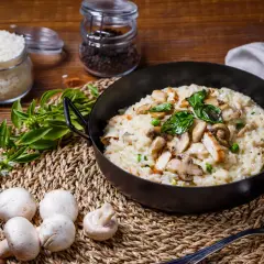 Risotto crémeux au poulet et champignons, garni de basilic frais.