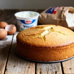 Gâteau doré sur fond de bois, avec des œufs, du yaourt et de la farine. Idéal pour une recette gâteau facile et rapide.