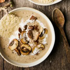Un réconfortant velouté de champignons, garni de champignons sautés, de crème et d'une tuile de parmesan croustillante.