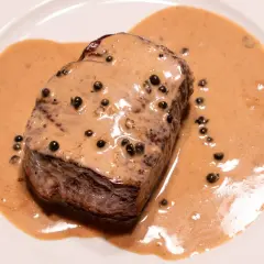 Un steak de bœuf nappé d'une onctueuse sauce au poivre, parfaite pour une recette de sauce au poivre réussie.