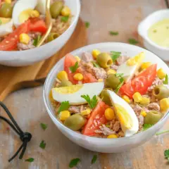 Salade niçoise au riz : thon, œufs durs, tomates, olives, maïs et persil frais. Un délice coloré.