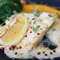 Filets de poisson nappés d'une sauce onctueuse, accompagnés d'une tranche de citron grillée et de légumes verts. Une sauce pour poisson parfaite pour sublimer ce plat.
