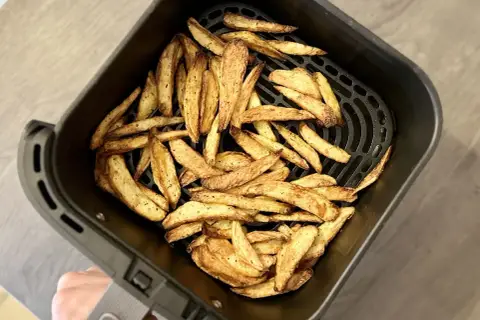 Un panier d'air fryer rempli de frites dorées et croustillantes, prêtes à être dégustées.
