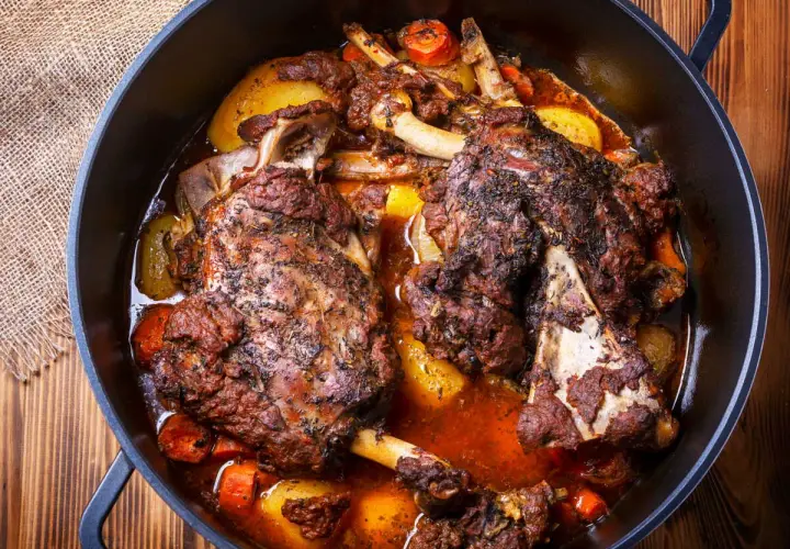 Deux épaules d'agneau en cocotte, tendres et savoureuses, mijotent avec des pommes de terre et des carottes dans un jus parfumé.