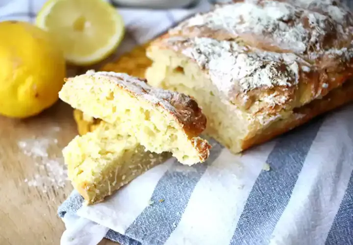 Pain sans levure, doré et saupoudré de farine, avec des citrons frais à côté.