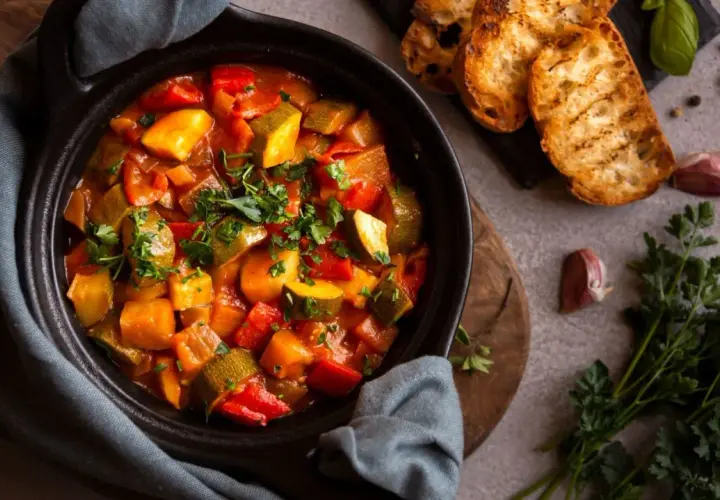 Ratatouille colorée dans un plat noir, servie avec des toasts grillés. Parfait pour savoir que manger avec une ratatouille.