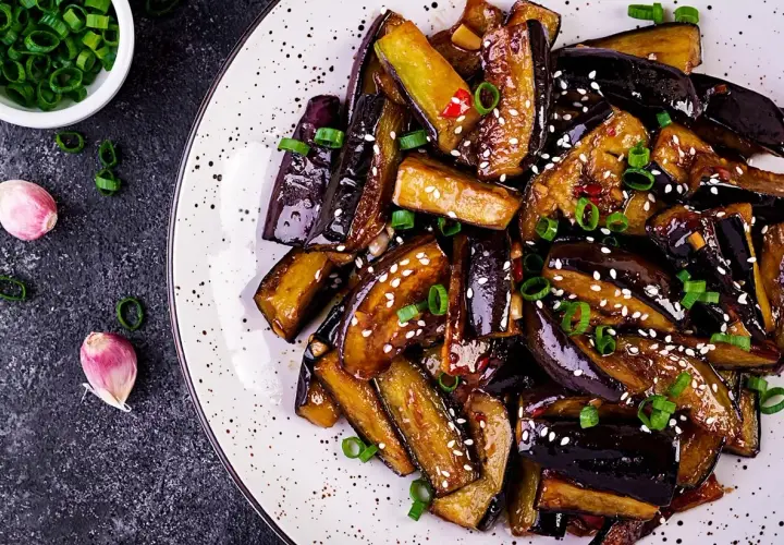 Aubergines poêlées, caramélisées et garnies de sésame et ciboule. Une recette simple et savoureuse pour sublimer ce légume.