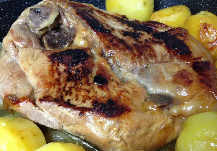 Rouelle de porc dorée et juteuse, accompagnée de pommes de terre fondantes, prête à être dégustée.