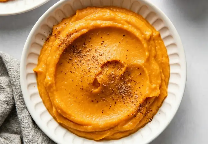 Un bol de purée de patate douce onctueuse, saupoudrée d'herbes. Un délice réconfortant.