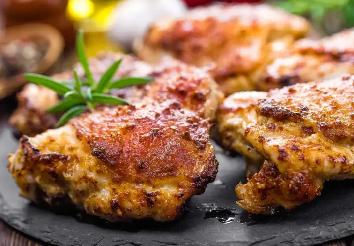 Délicieuses cuisses de poulet Cookeo dorées et croustillantes, garnies de romarin frais sur une assiette en ardoise.