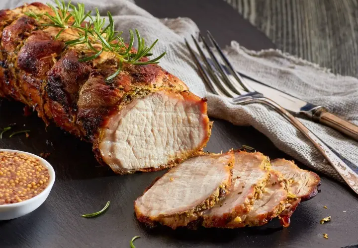 Un délicieux roti de porc Cookeo, tendre et juteux, servi avec de la moutarde à l'ancienne et des herbes fraîches.