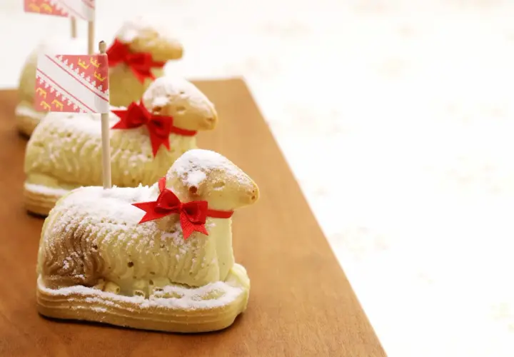 Trois agneaux en biscuit, saupoudrés de sucre glace et ornés de rubans rouges, rappellent la recette lamala grand-mère.