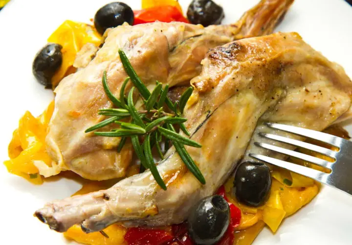 Délicieux lapin au Cookeo, servi avec des poivrons colorés, des olives noires et une touche de romarin frais.