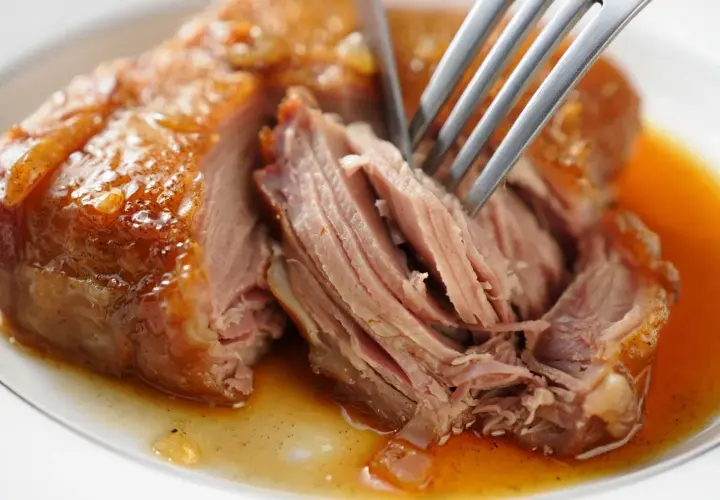 Une rouelle de porc juteuse, effilochée à la fourchette, baignant dans sa sauce dorée. Un délice pour une recette de rouelle de porc réussie.