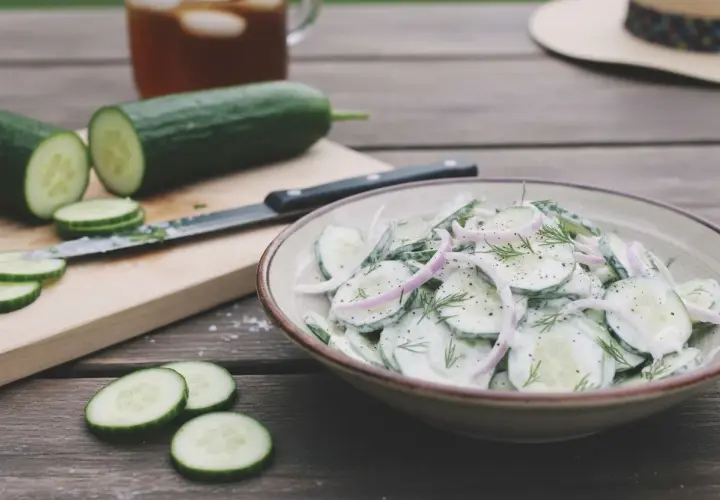 Une délicieuse salade de concombre crémeuse, garnie d'oignons rouges et d'aneth, prête à être dégustée par une chaude journée.