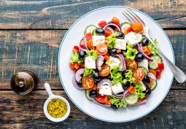 Salade grecque colorée avec feta, olives, tomates, concombre et oignons rouges. Une recette fraîche et légère.