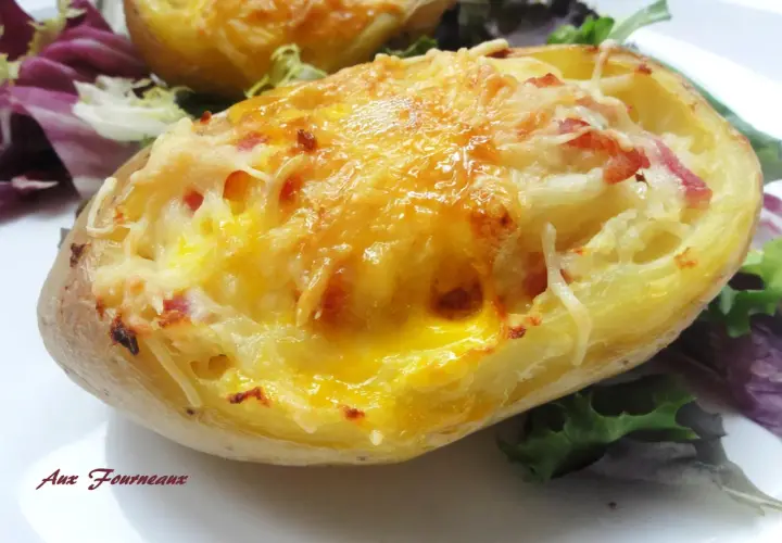 Une pomme de terre farcie, gratinée au fromage et garnie de lardons, servie avec une salade verte.
