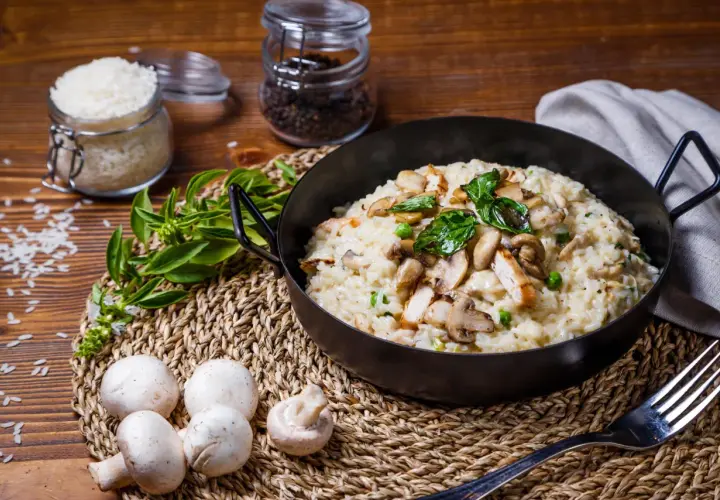 Risotto crémeux au poulet et champignons, garni de basilic frais.
