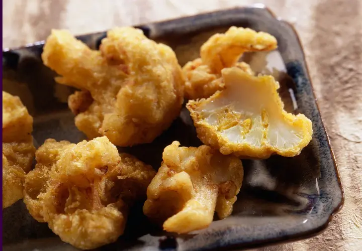 Beignets de chou-fleur dorés et croustillants, servis sur un plateau. Un délice à croquer !
