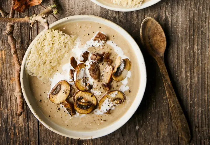 Un réconfortant velouté de champignons, garni de champignons sautés, de crème et d'une tuile de parmesan croustillante.