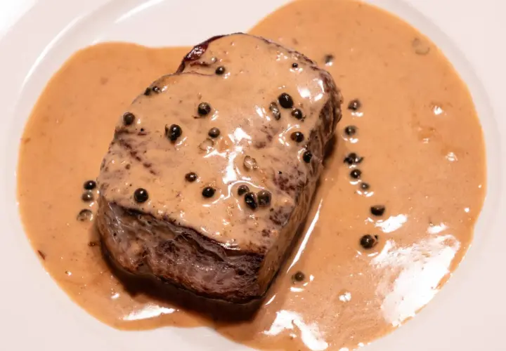 Un steak de bœuf nappé d'une onctueuse sauce au poivre, parfaite pour une recette de sauce au poivre réussie.