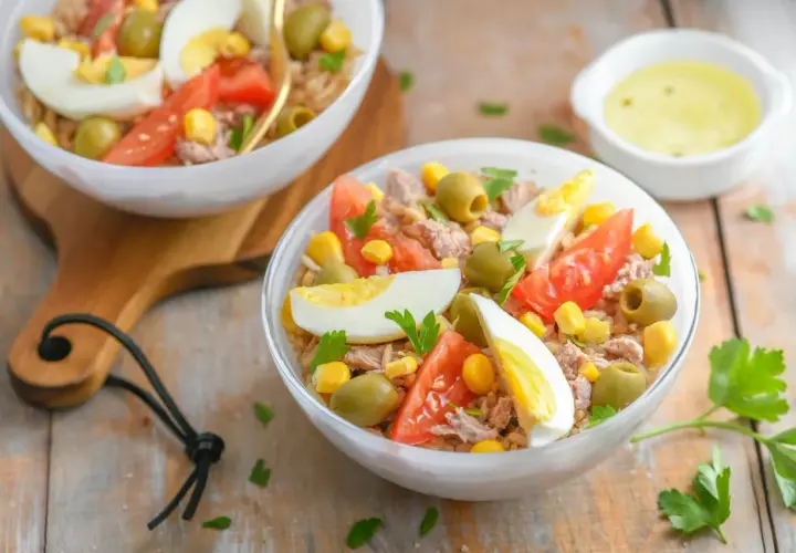 Salade niçoise au riz : thon, œufs durs, tomates, olives, maïs et persil frais. Un délice coloré.