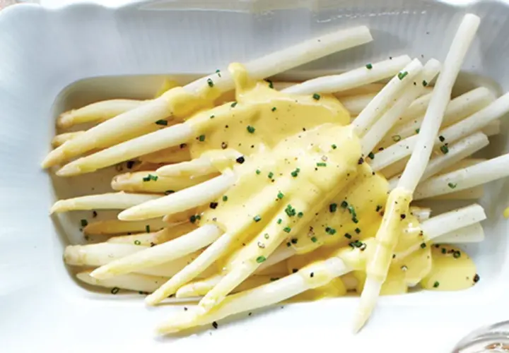 Asperges blanches tendres nappées d'une sauce crémeuse et garnies de ciboulette. Un délice printanier à déguster avec cette sauce pour asperges blanches.