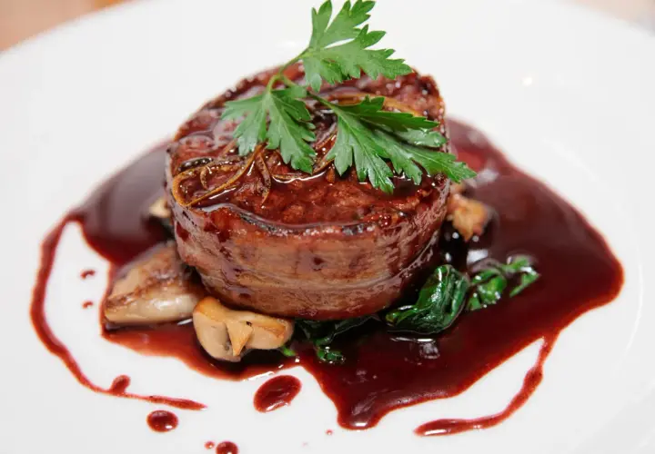 Un tendre filet de bœuf enrobé de lard, nappé d'une riche sauce marchand de vin, accompagné de champignons et d'épinards.