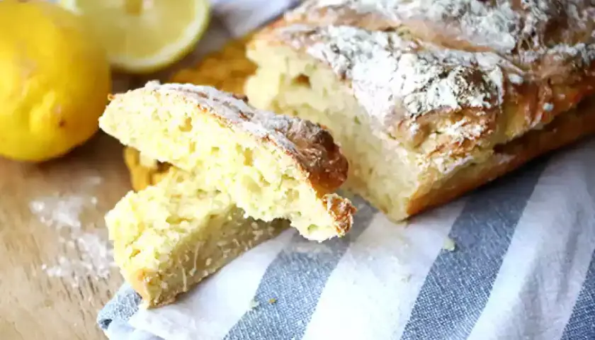 Pain sans levure, doré et saupoudré de farine, avec des citrons frais à côté.