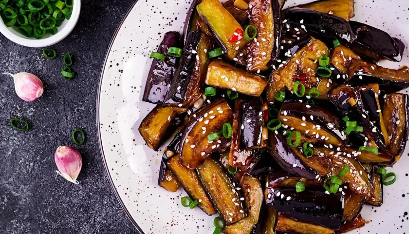 Aubergines poêlées, caramélisées et garnies de sésame et ciboule. Une recette simple et savoureuse pour sublimer ce légume.