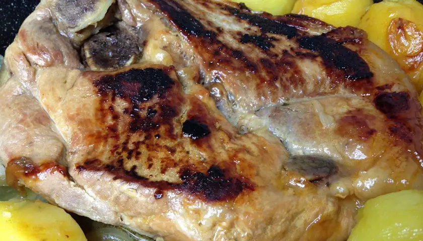 Rouelle de porc dorée et juteuse, accompagnée de pommes de terre fondantes, prête à être dégustée.