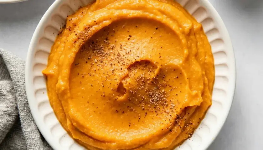 Un bol de purée de patate douce onctueuse, saupoudrée d'herbes. Un délice réconfortant.