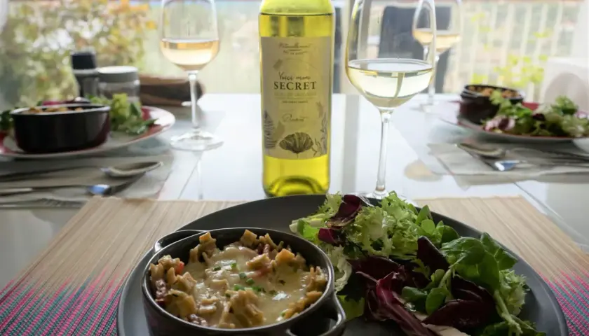 Un gratin de crozet savoureux, servi avec une salade fraîche et un verre de vin blanc. Un repas simple et délicieux.