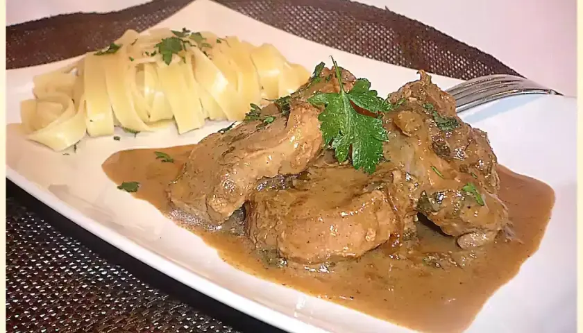 Délicieux filet mignon moutarde en sauce, servi avec des pâtes fraîches et garni de persil. Un plat savoureux.