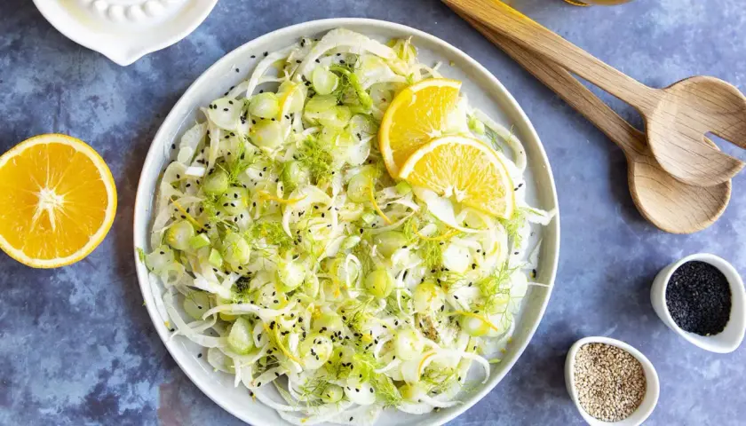 Salade de fenouil frais avec des tranches d'orange, du zeste et des graines de sésame noir. Un délice léger et croquant, parfait pour accompagner un plat.