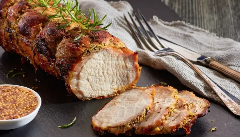 Un délicieux roti de porc Cookeo, tendre et juteux, servi avec de la moutarde à l'ancienne et des herbes fraîches.